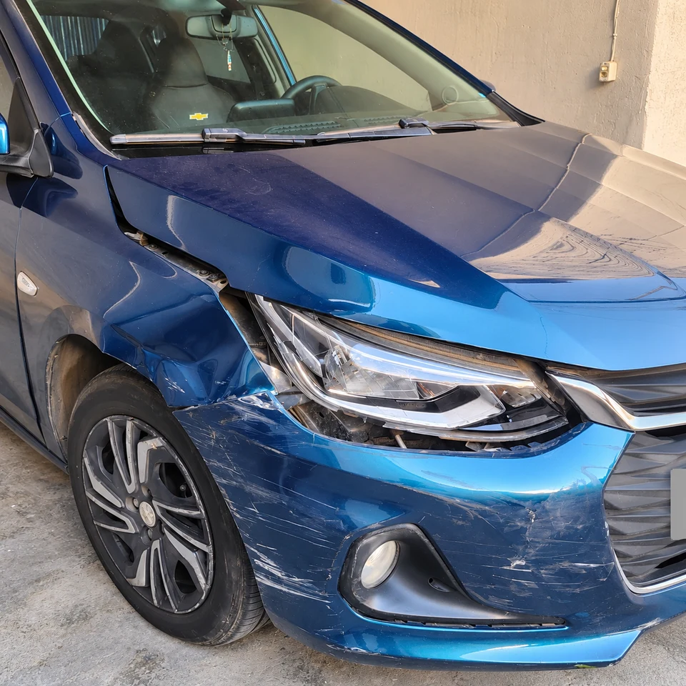 Chevrolet azul na chegada: para-lama amassado, para-choque riscado e peças desalinhadas